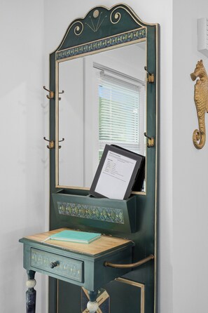Een wastafelmeubel met spiegel, een klein bureau en een decoratief object aan de wand.