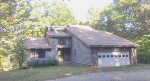 A two-story house with a garage, surrounded by trees. - 4 BR Mountain Retreat in Stunning Hardwood Forest: Big Views & Friendly Goats (Blairsville)