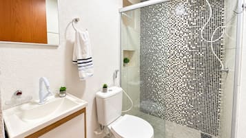 Een moderne badkamer met een wit wastafel, toilet en douche met een mozaïektegel muur.