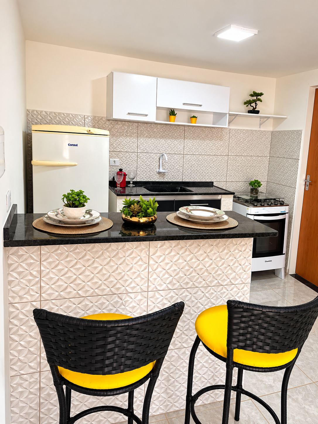 Una cocina moderna con refrigerador, estufa y dos taburetes de bar.