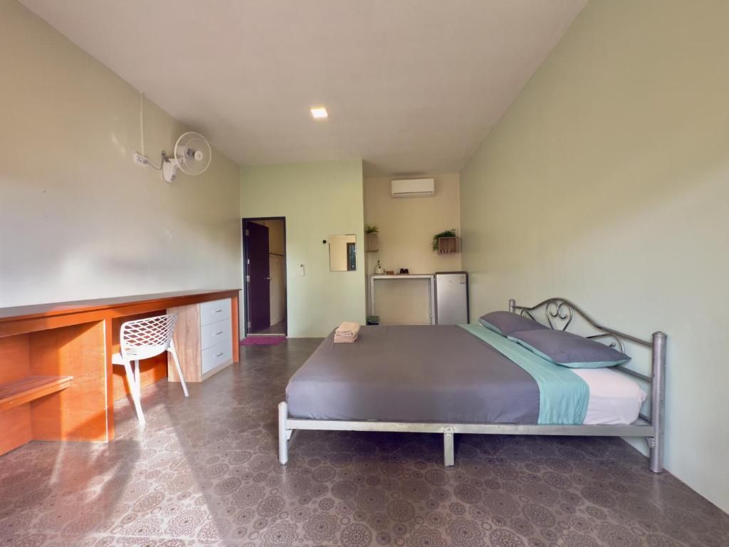 A bedroom with a bed, desk, chair, and a small kitchenette area.
