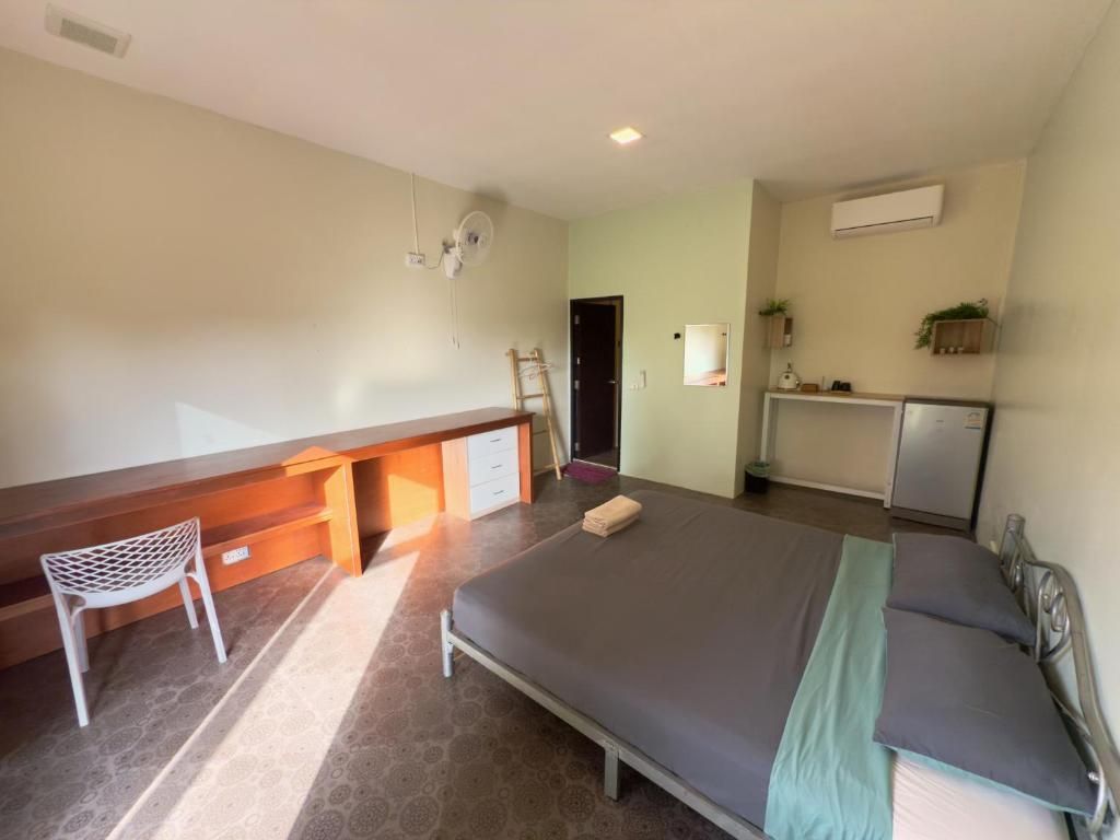 A room with a bed, a desk, a chair, and a small kitchenette area.