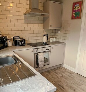 A compact kitchen with a stove, oven, and a microwave. - Cosy house 5 mins walk from the sea. (Cleethorpes)
