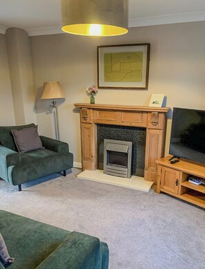 A living room with a fireplace, a television, and a sofa. - Cosy house 5 mins walk from the sea. (Cleethorpes)