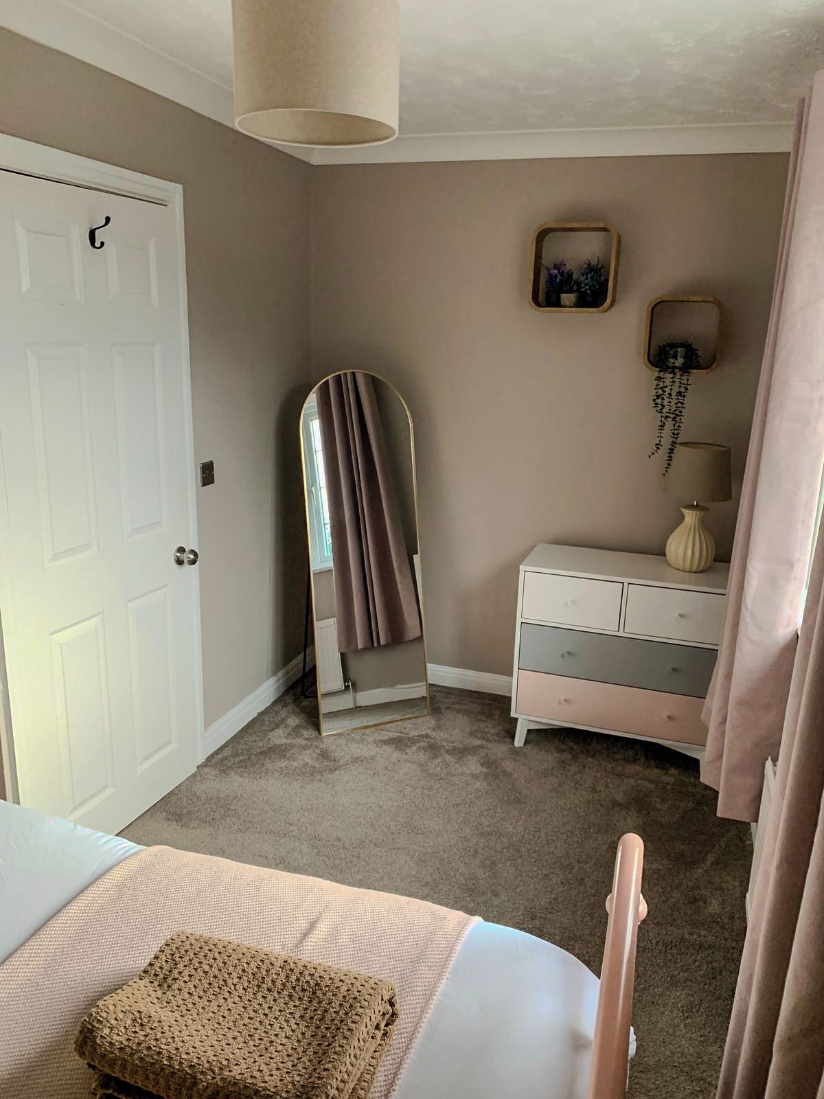 Ein Zimmer mit einer weißen Tür, einem Spiegel, einem Schminktisch und einer Lampe.