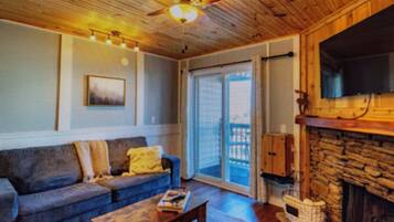 A room with a fireplace, a sofa, a coffee table, and a television.