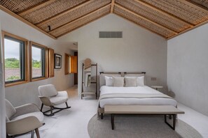 Quarto com cama, cadeira, mesa de cabeceira e janela.