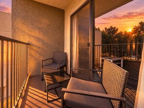 A balcony with a sofa, two chairs, and a table, overlooking a sunset. - Pool | Gym | Great For Mid/Long Stays (Mesa)