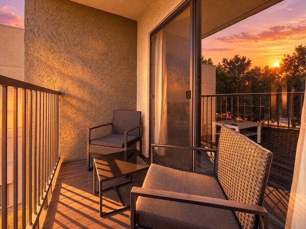 A balcony with a sofa, two chairs, and a table, overlooking a sunset. - Pool | Gym | Great For Mid/Long Stays (Mesa)