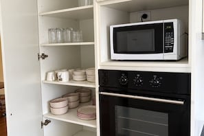 A kitchen with a microwave on the upper shelf and an oven below. - Ferguson House – Cosy Hunter Valley Escape (Cessnock)