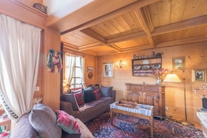A cozy wooden interior with a sofa, a coffee table, and a cabinet. - Le Panorama Montagnard - Welkeys (Combloux)