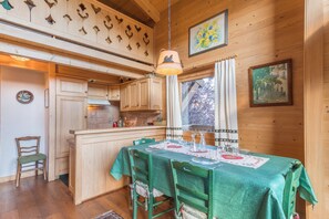 A cozy wooden interior with a dining area, wooden cabinets, and a kitchen. - Le Panorama Montagnard - Welkeys (Combloux)