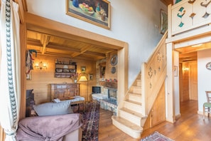 A cozy interior with a wooden staircase, a fireplace, and a dining area with a table and chairs. - Le Panorama Montagnard - Welkeys (Combloux)
