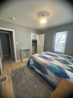 Un dormitorio con cama, puerta, armario y ventana.