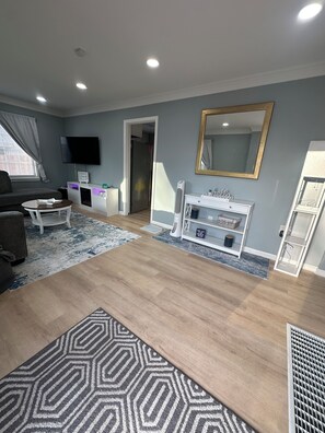 A modern living room with a flat-screen TV, a sofa, a coffee table, and a patterned rug. - Cozy 2-bedroom house in peaceful Speedway close to the track! (Speedway)