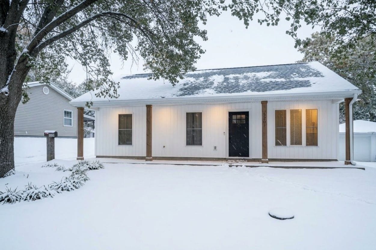 A single-story house with a snow-covered roof and a front door.