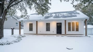A single-story house with a snow-covered roof and a front door.