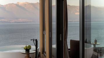 A modern interior with a glass balustrade overlooking a body of water and mountains.