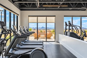 A gym with multiple treadmills, a seating area with a view of mountains, and large windows. - High Street Hideaway | Near Mayo Clinic & Shopping (Phoenix)