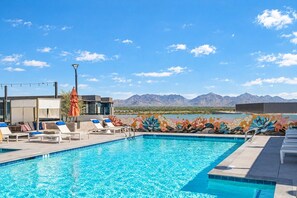 A swimming pool with lounge chairs and a mural, surrounded by mountains. - High Street Hideaway | Near Mayo Clinic & Shopping (Phoenix)