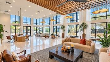 Un amplio vestíbulo de hotel con techo alto, ventanas grandes y una zona de estar central con sofás y sillones.