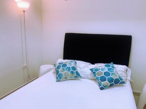 A bed with a black headboard, white bedding, and two patterned pillows. - A12 en El Laguito: cerca del mar, piscina y aire acondicionado (CARTAGENA DE INDIAS)