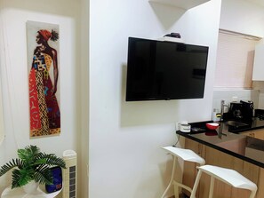 A modern kitchen with a flat-screen TV, a coffee maker, and a small bar area. - A12 en El Laguito: cerca del mar, piscina y aire acondicionado (CARTAGENA DE INDIAS)