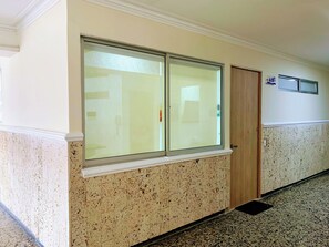 Un passadís amb una porta doble, una finestra i un termòstat fixat a la paret.