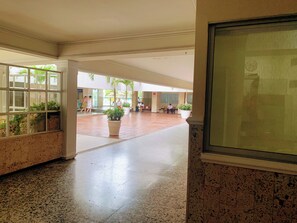 A spacious indoor area with a polished floor, large windows, and potted plants. - A12 en El Laguito: cerca del mar, piscina y aire acondicionado (CARTAGENA DE INDIAS)