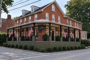 A brick building with a covered porch, American flags, and a sign reading 'The Chatham by Foraker Realty Co.' - Equestrian 2BR near Longwood Gardens & Kennett Sq (West Grove)