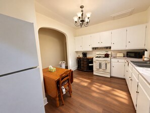 A kitchen with white cabinets, a wooden dining table, a chandelier, and a built-in oven. - Equestrian 2BR near Longwood Gardens & Kennett Sq (West Grove)