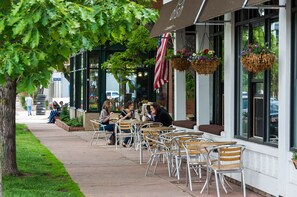 An outdoor cafe with tables and chairs, a building with large windows, and hanging flower baskets. - Stunning FURNISHED 1BR/1BA Condo in Downtown Boulder - Digital Nomad's Dream (Boulder)