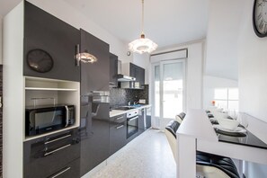 Une cuisine moderne équipée d’un four à micro-ondes, d’un four traditionnel et d’un coin repas avec une table dressée pour deux personnes.