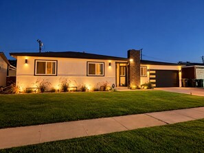 Une maison moderne à deux étages, dotée d’une pelouse bien entretenue et d’un garage.