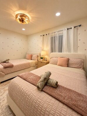A hotel room with two beds, a nightstand, a lamp, and a window with curtains. - Luxury Remodel Disney Retreat With Game Room & Private Yard (Anaheim)