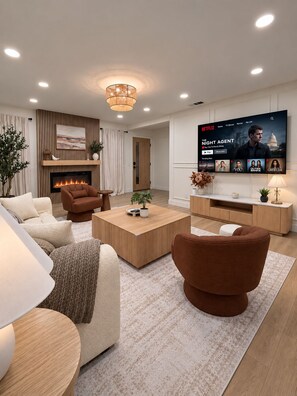 A modern living room with a fireplace, a flat-screen TV, and a cozy seating area. - Luxury Remodel Disney Retreat With Game Room & Private Yard (Anaheim)