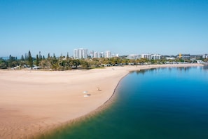 A coastal beach with a clear sky, a sandy shore, and a calm sea. - Muroy - Beachside Apartment @ Cotton Tree (Maroochydore)
