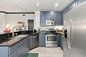 A modern kitchen with grey cabinets, stainless steel appliances, and a black countertop. - Kissimmee Family Home | 3BR, 2BA & Laundry (Kissimee)
