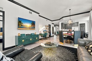 A modern living room with a sofa, a coffee table, and a dining area with a table and chairs. - Kissimmee Family Home | 3BR, 2BA & Laundry (Kissimee)