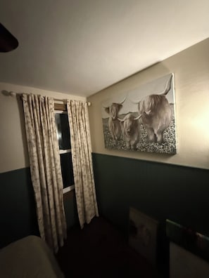 A room with a bed, a window with curtains, and a wall-mounted painting of two yaks. - Boho Bungalow walking distance from Notre Dame (South Bend)