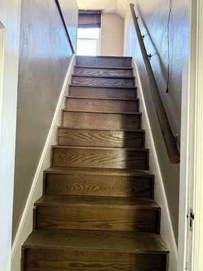 A wooden staircase with a handrail, leading to an upper floor. - Boho Bungalow walking distance from Notre Dame (South Bend)