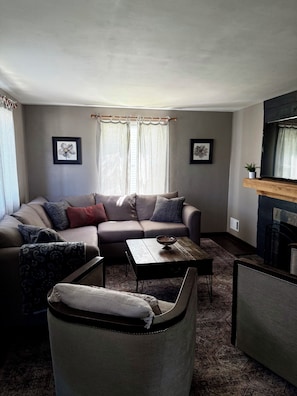A living room with a sectional sofa, a coffee table, and a patterned rug. - Boho Bungalow walking distance from Notre Dame (South Bend)