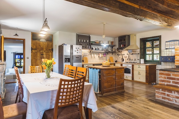 A kitchen with wooden cabinets, a dining table with chairs, and a central island. - Charming Wooden Holiday Home in Zagorje with Jacuzzi, Sauna and Large Estate (Donja Stubica)