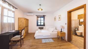 A bedroom with a bed, bedside table, chair, desk, and a window with curtains.