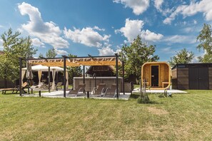 A covered outdoor seating area with lounge chairs and a pergola structure. - Charming Wooden Holiday Home in Zagorje with Jacuzzi, Sauna and Large Estate (Donja Stubica)