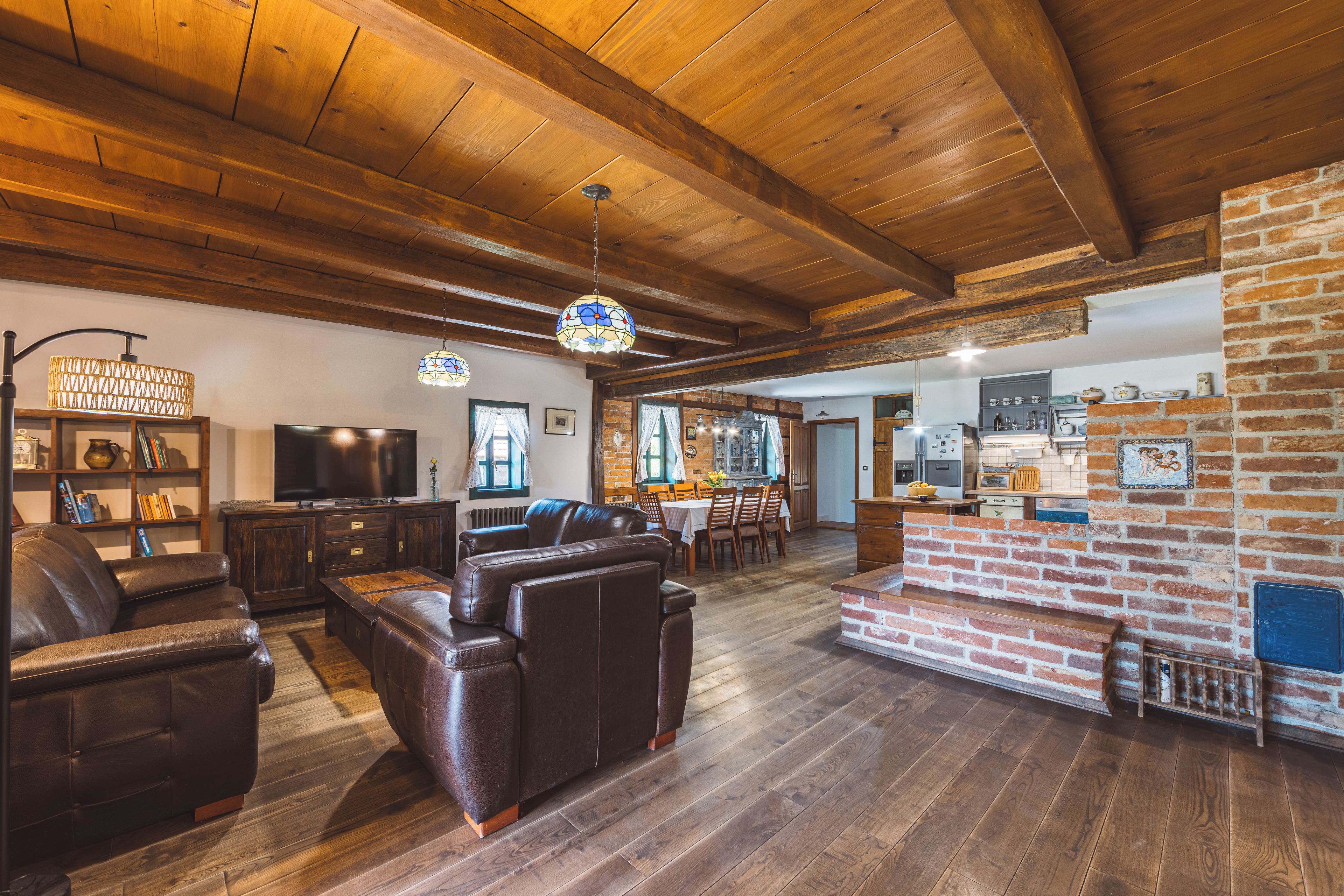 A spacious living room with a fireplace, leather sofas, and a television.