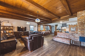 A spacious living room with a fireplace, leather sofas, and a television. - Charming Wooden Holiday Home in Zagorje with Jacuzzi, Sauna and Large Estate (Donja Stubica)