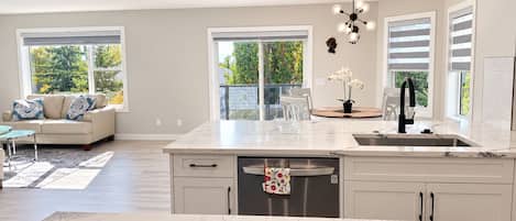 A modern kitchen with a marble countertop, a dishwasher, and a dining area with a sofa and chairs.