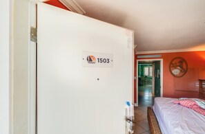 A hotel room with a bed, a door with a number sign, and a hallway leading to another room. - Stay at Bluewater with Balcony,Beach & Pool Access (Myrtle Beach)