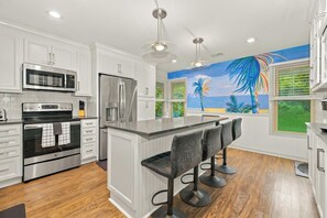 A modern kitchen with white cabinetry, stainless steel appliances, and a central island with bar stools. - 3 Ocean Park Court, Isle of Palms (Isle of Palms)